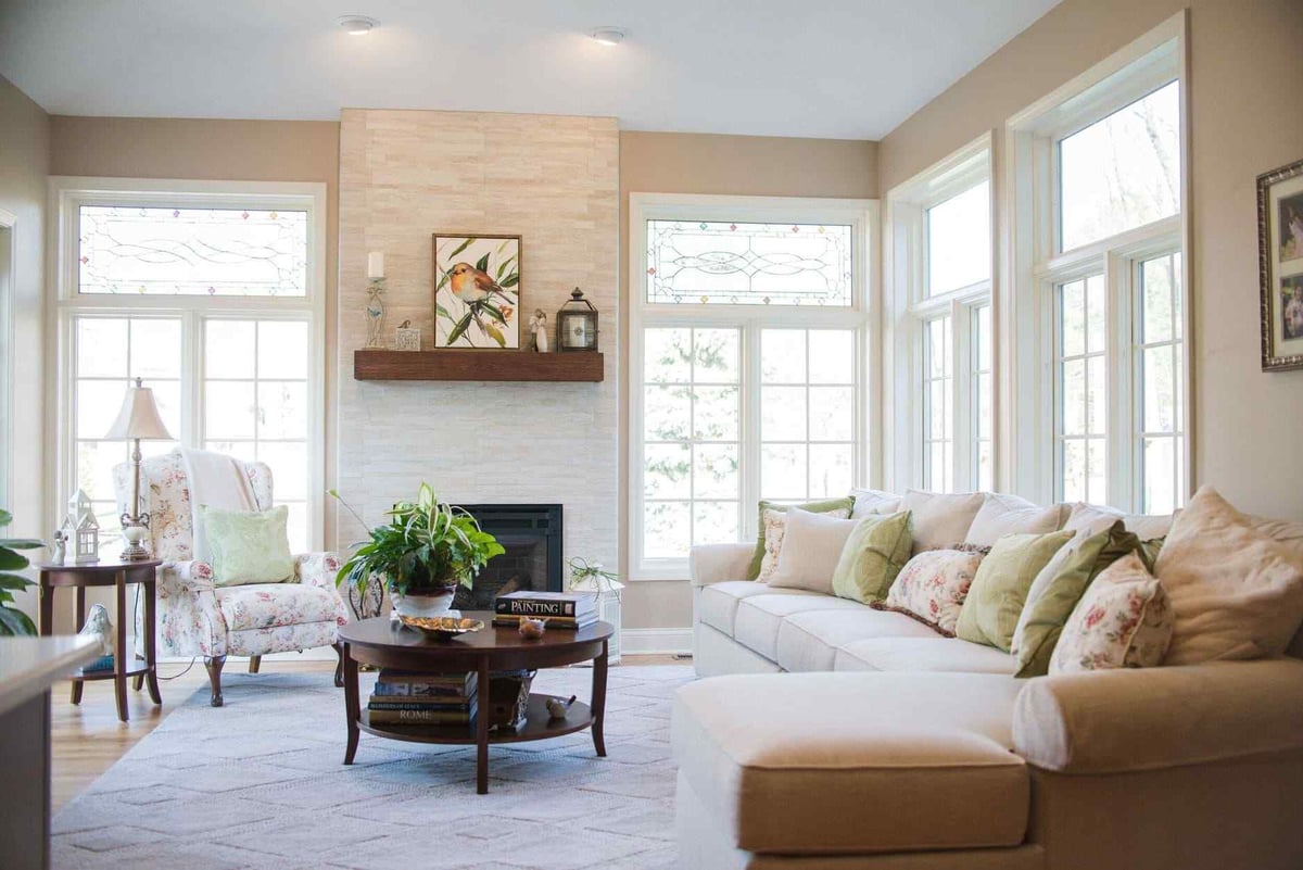 Sunroom interior with white trim windows and natural stone fireplace in between by Peacock and Company