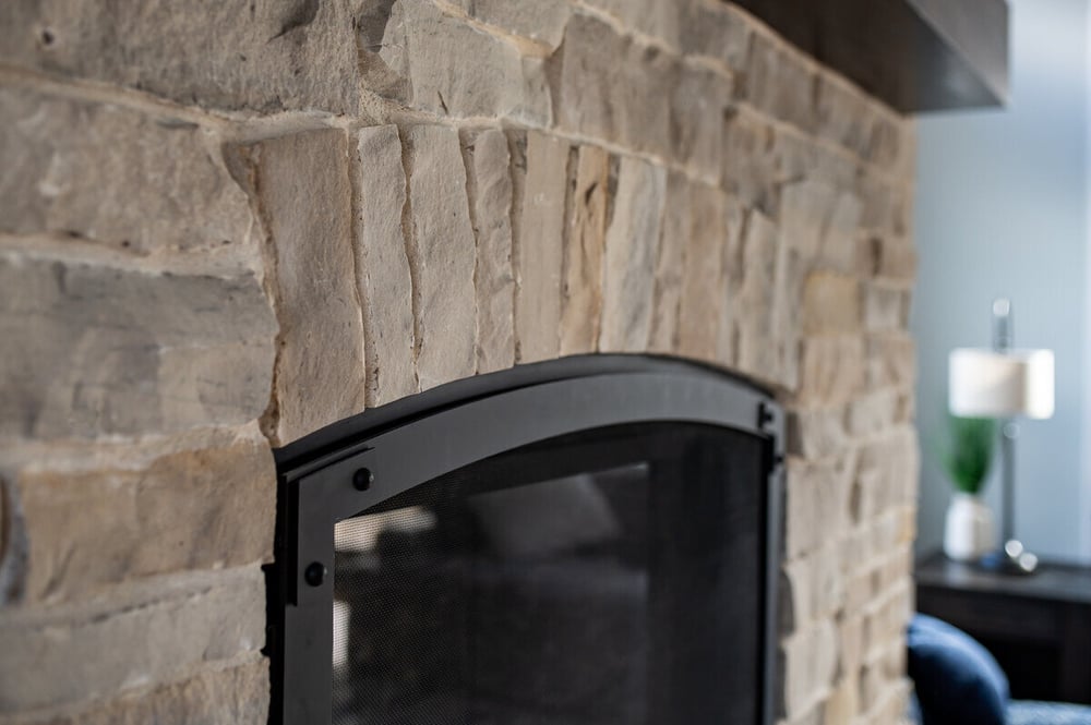 Up-close view of fireplace with stone surround by Peacock and Company