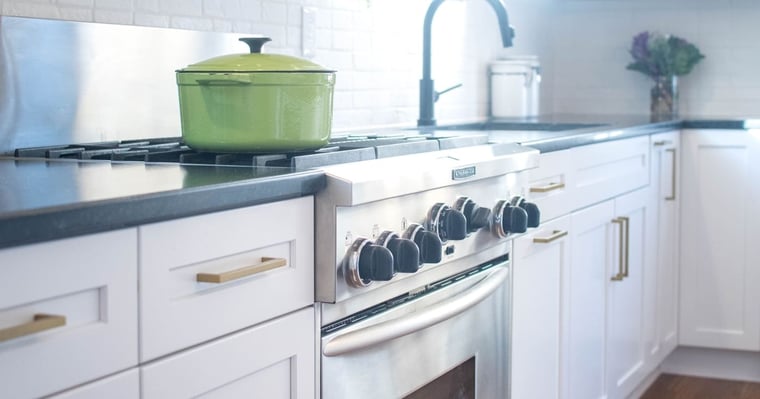 White shaker cabinets with brass pulls and stainless steel oven
