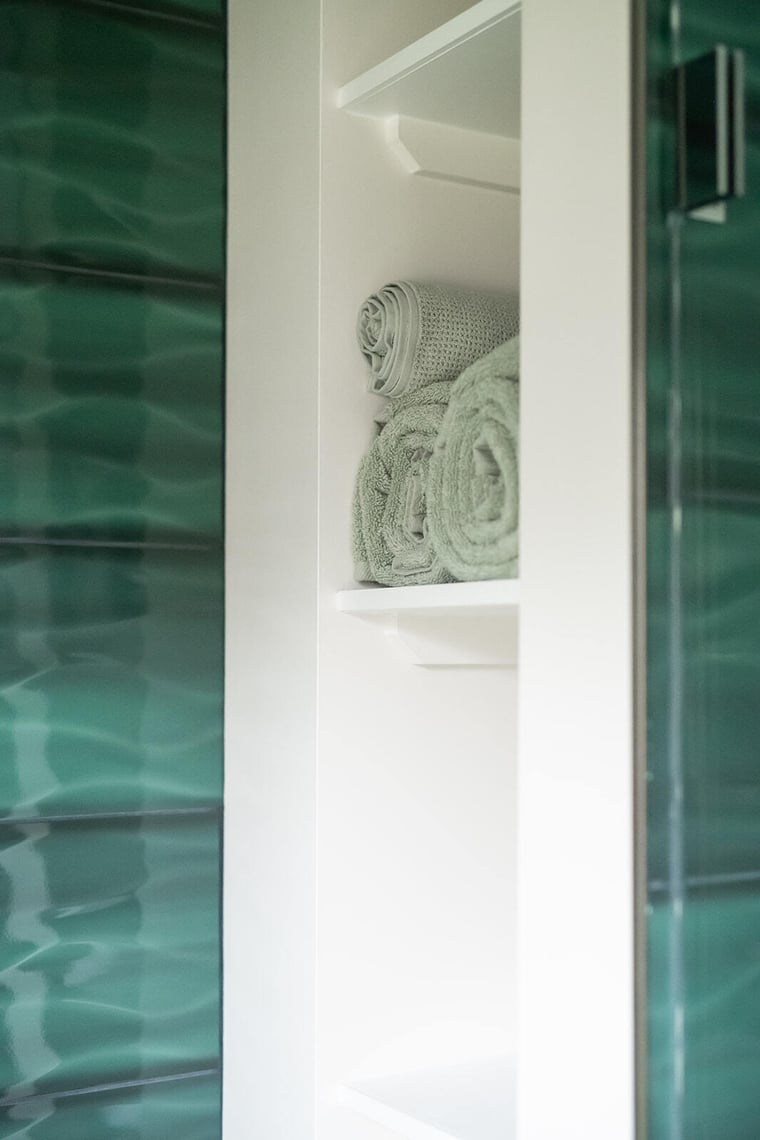 Peacock & Co. close up of built in storage amid green tile accent wall in south bend bathroom remodel