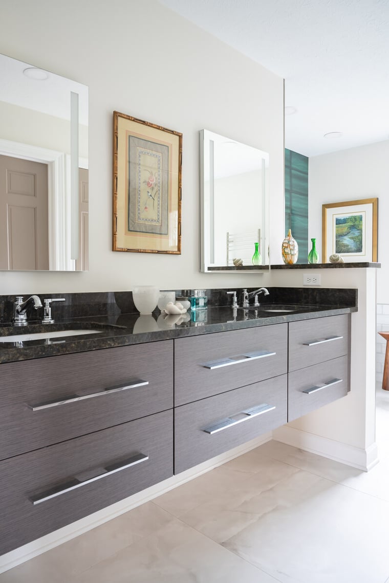 Peacock & Co.- South Bend bathroom remodel with dark wood floating vanity with wide handles, two sinks, black countertop, and custom lit mirrors