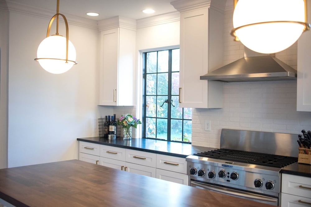 circular pendant lighting white kitchen aid stove and range hood white brick backsplash