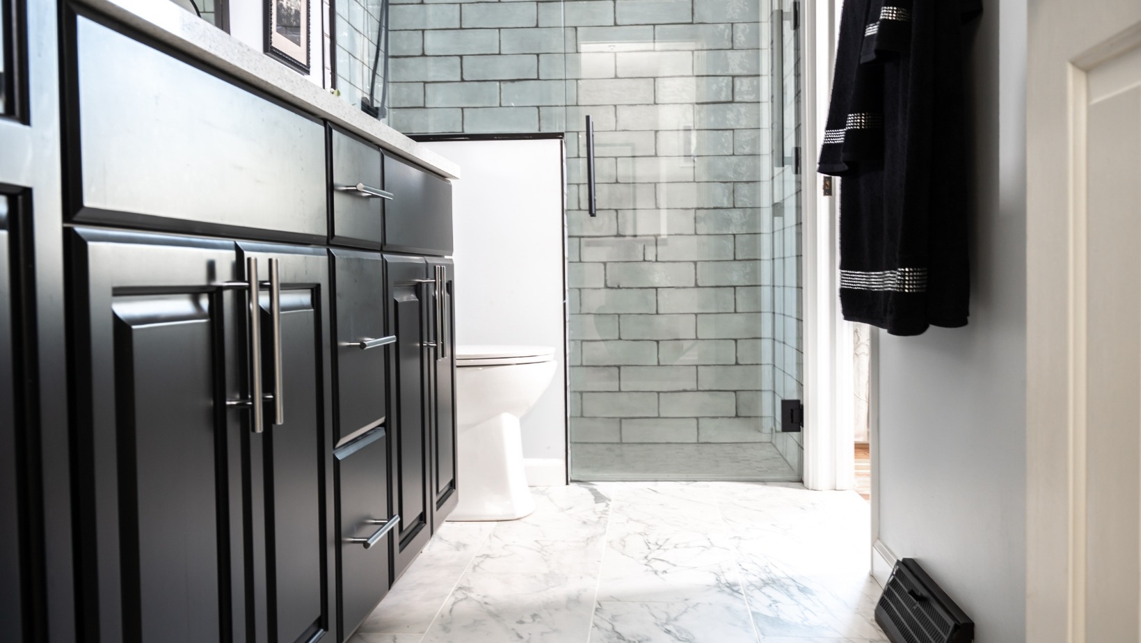 Dark cabinets with luxury marble flooring in modern bathroom remodel