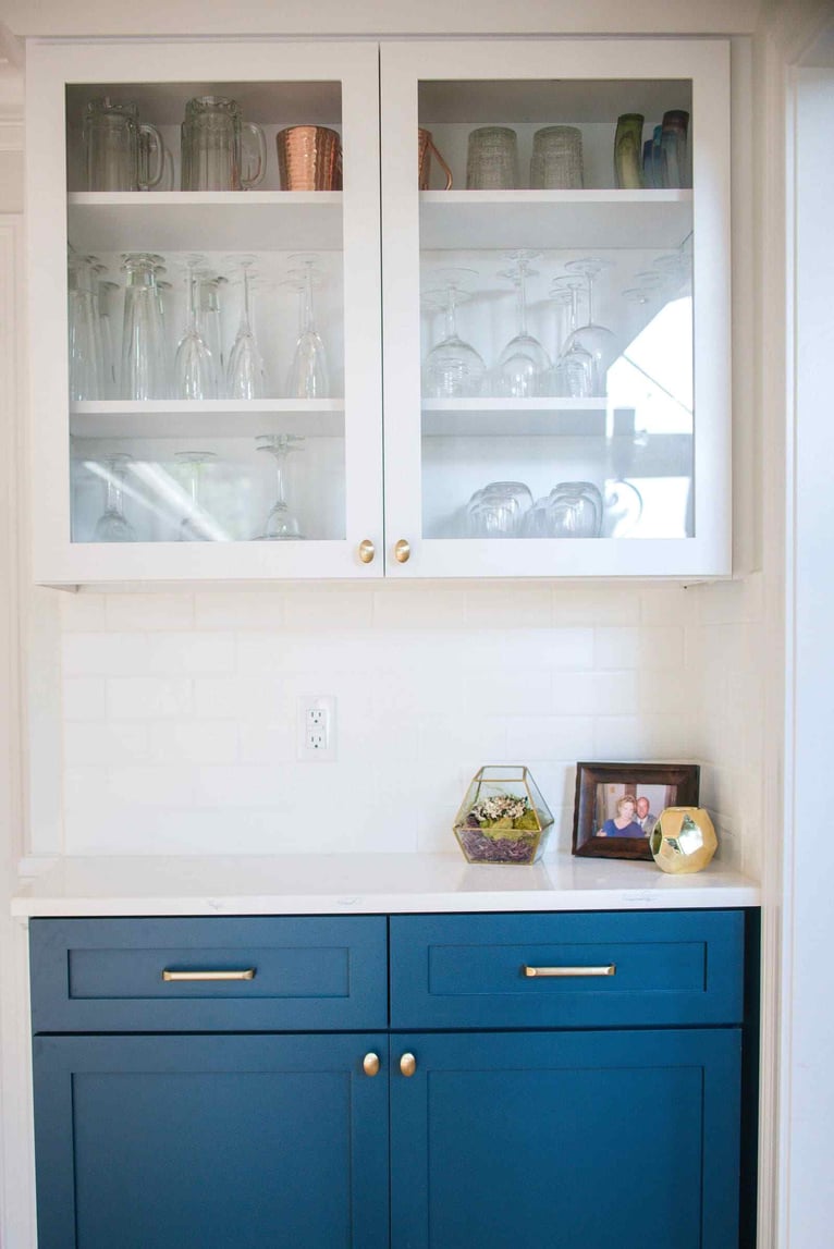 Two-tone kitchen remodel with bold blue cabinets beneath glass cabinets