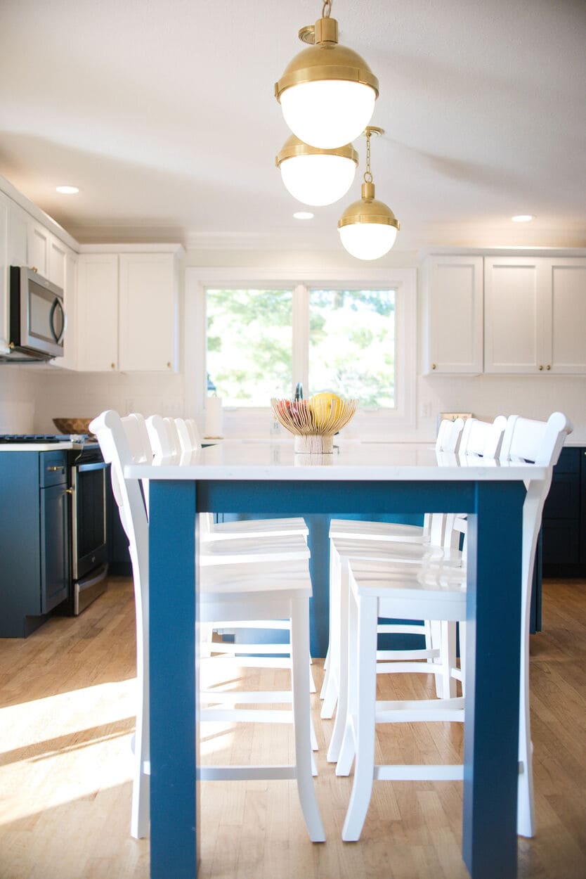 Two-tone kitchen remodel with dining room table beneath pendant lighting