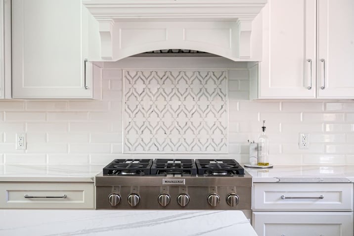 White kitchen remodel with stainless steel range and tile backsplash
