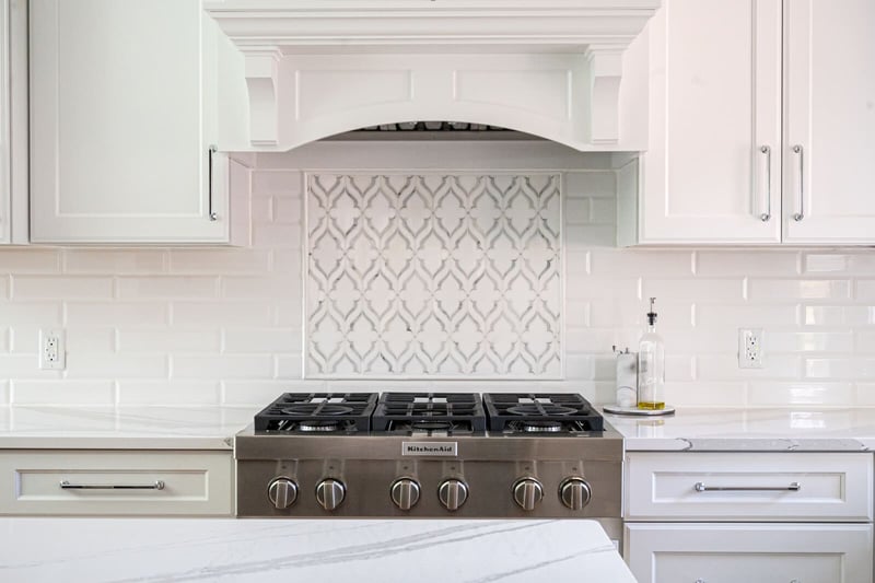 White kitchen remodel with stainless steel range and tile backsplash