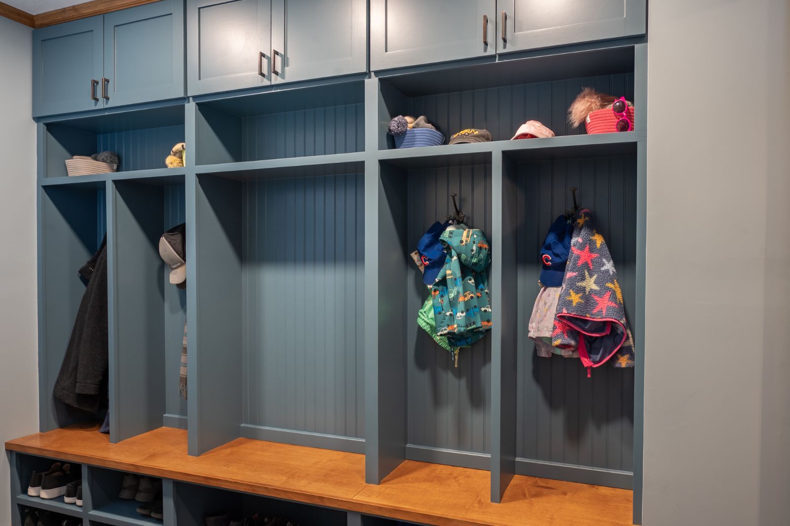 Built-in blue mudroom lockers with wood bench and storage cubbies located in Granger, IN