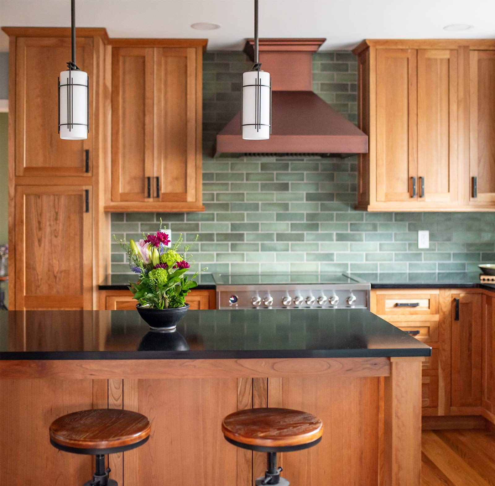 Michiana area kitchen with wood cabinets, green tile backsplash, and black countertop island Michiana area kitchen with wood cabinets, green tile backsplash, and black countertop island